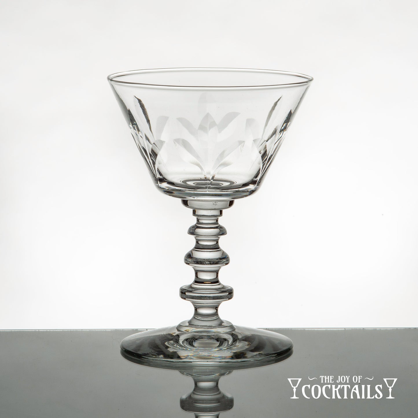 Rock Sharpe Fleur de Lis cocktail glass on a reflective surface with a white background