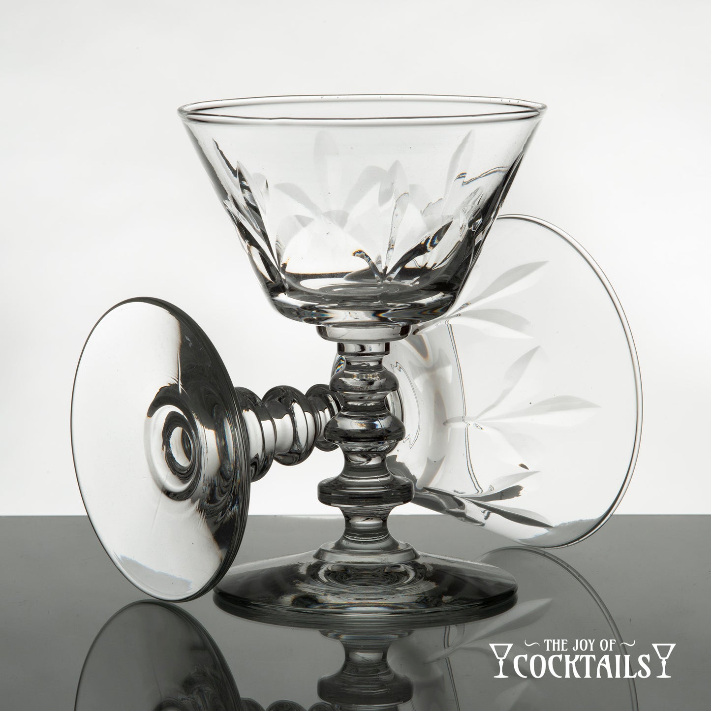 Rock Sharpe Fleur de Lis cocktail glass on a reflective surface with a white background