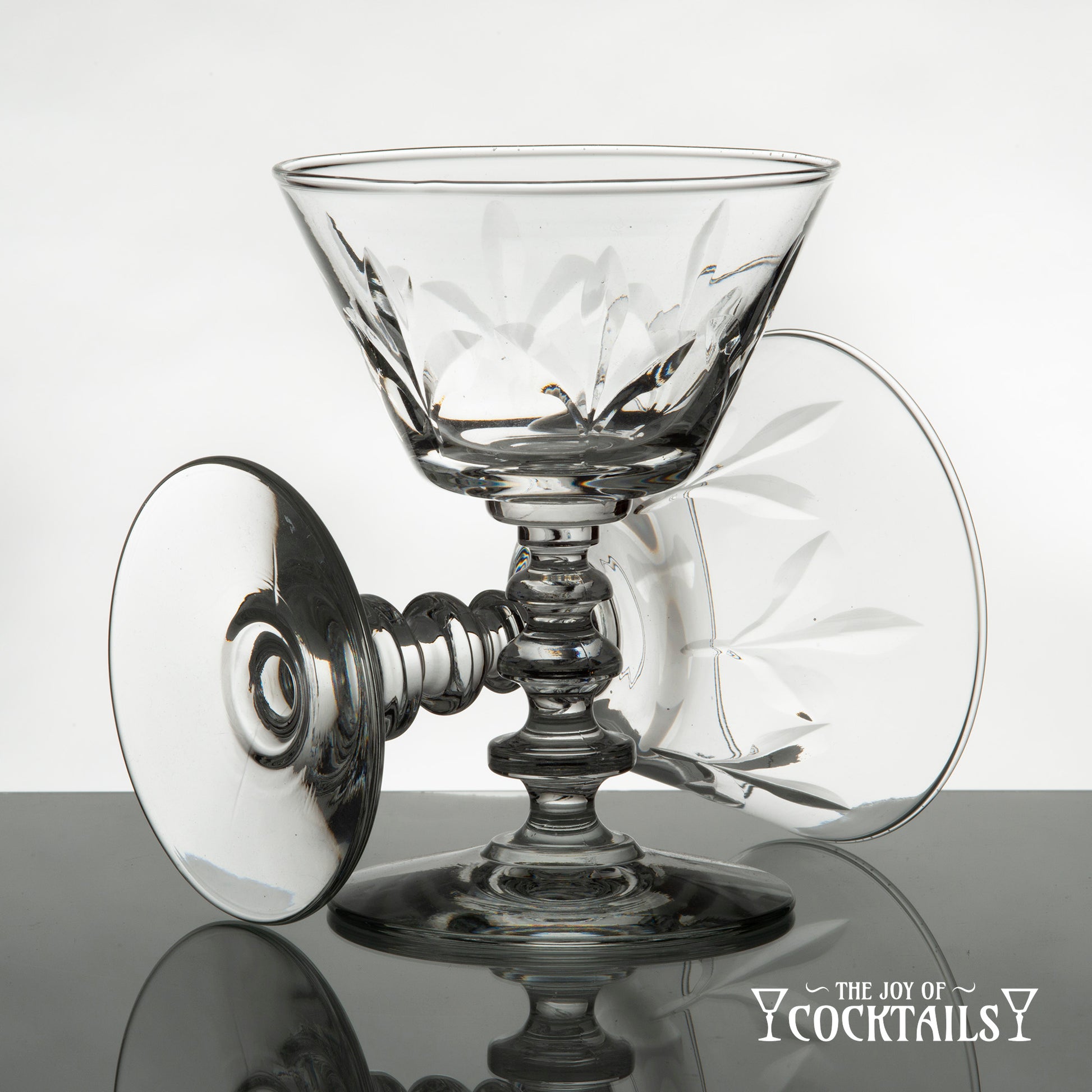 Rock Sharpe Fleur de Lis cocktail glass on a reflective surface with a white background