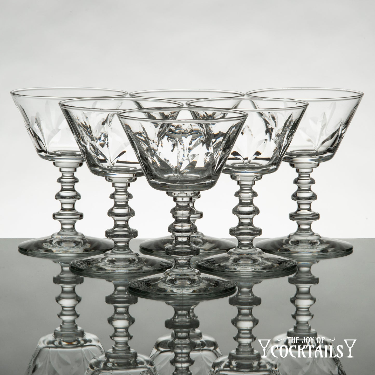 Rock Sharpe Fleur de Lis cocktail glass on a reflective surface with a white background