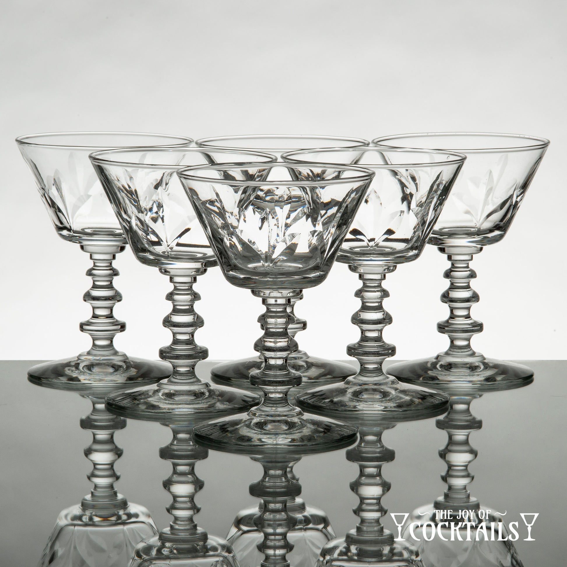 Rock Sharpe Fleur de Lis cocktail glass on a reflective surface with a white background
